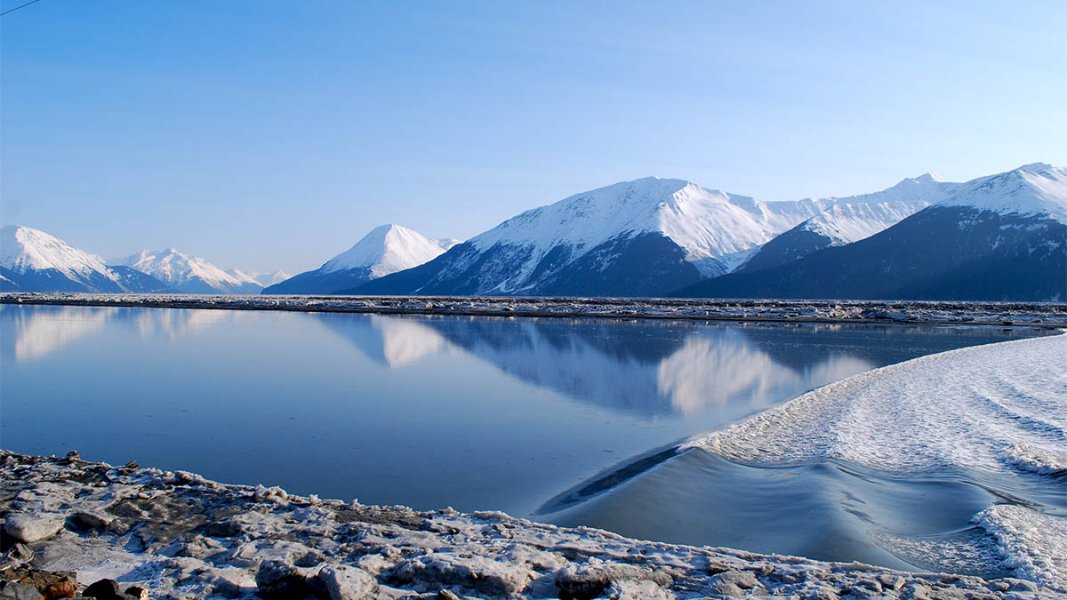 Lake surrounded by snow-capped mountains in distance.
