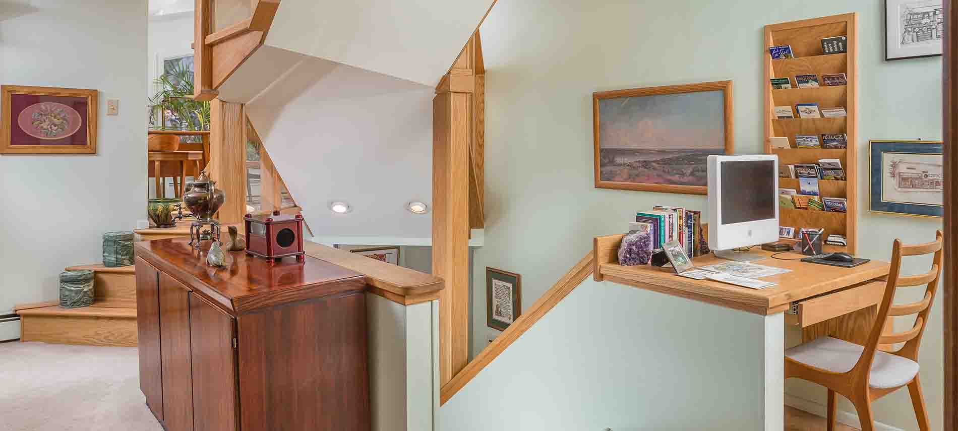 Light green room at top of stairs; walnut counter top with computer; walnut rack card display built into wall