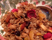 Flowered round bowl with silver spoon containing granola and dried strawberries.