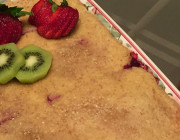 Rectangular dish with pastry, fresh kiwi and strawberries with stems, Cantaloupe and green grapes on glass dish.